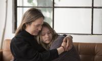 En mor holder om sin triste datter i en sofa