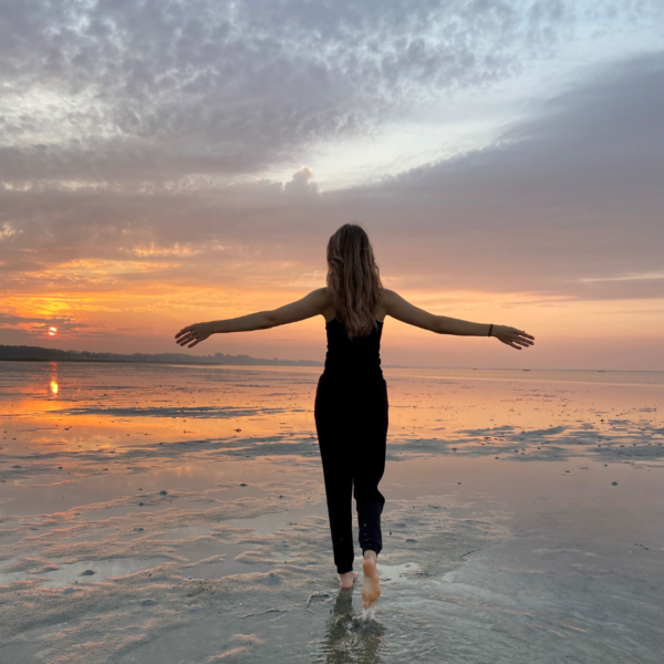 Astrid Lucina der går mod solnedgangen på stranden