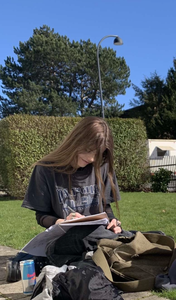 Chris der sidder og skriver i en park