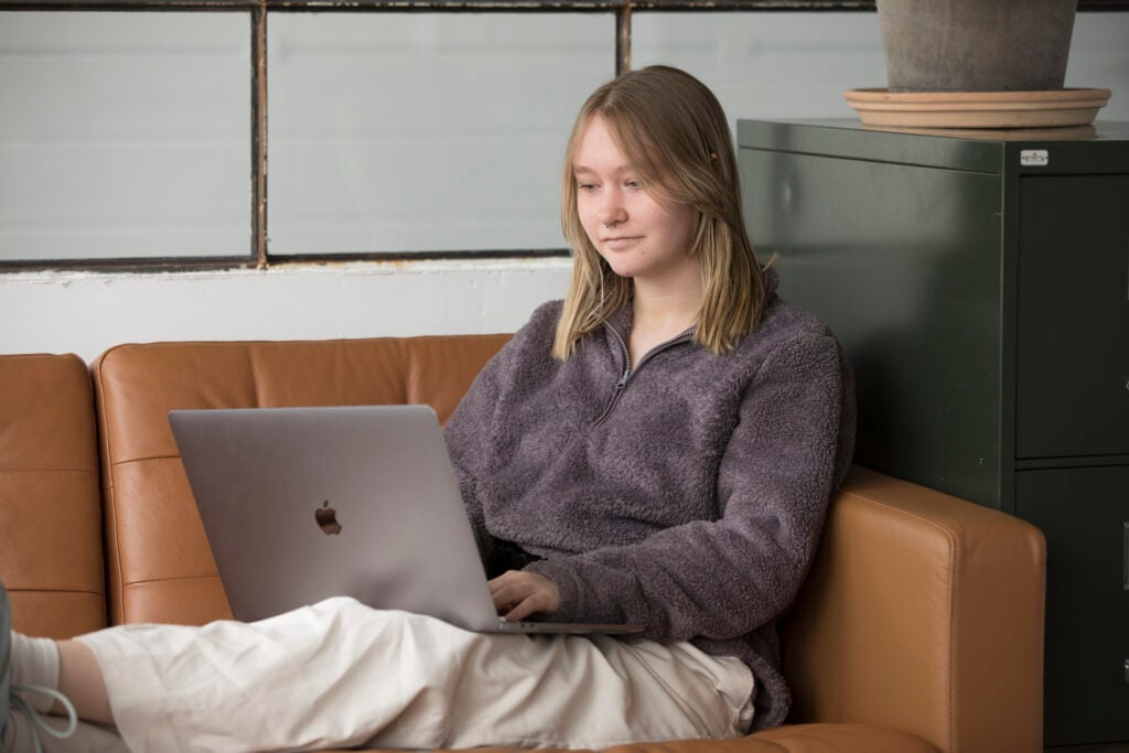 Ung kvinde der sidder i en sofa med en computer